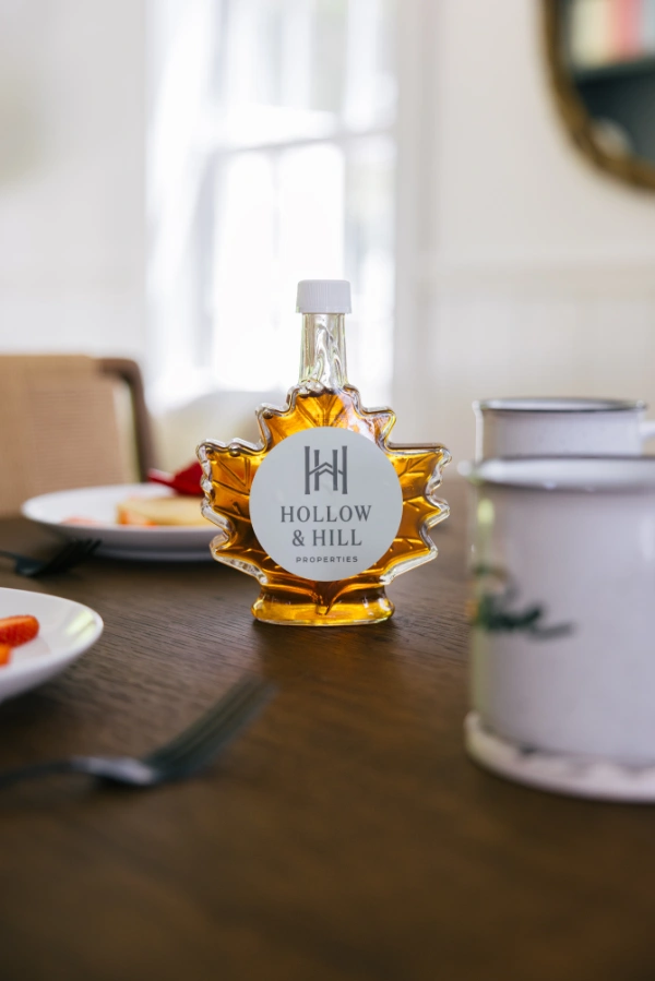 Breakfast table setting with maple syrup bottle, coffee mug, and morning light creating a cozy dining atmosphere